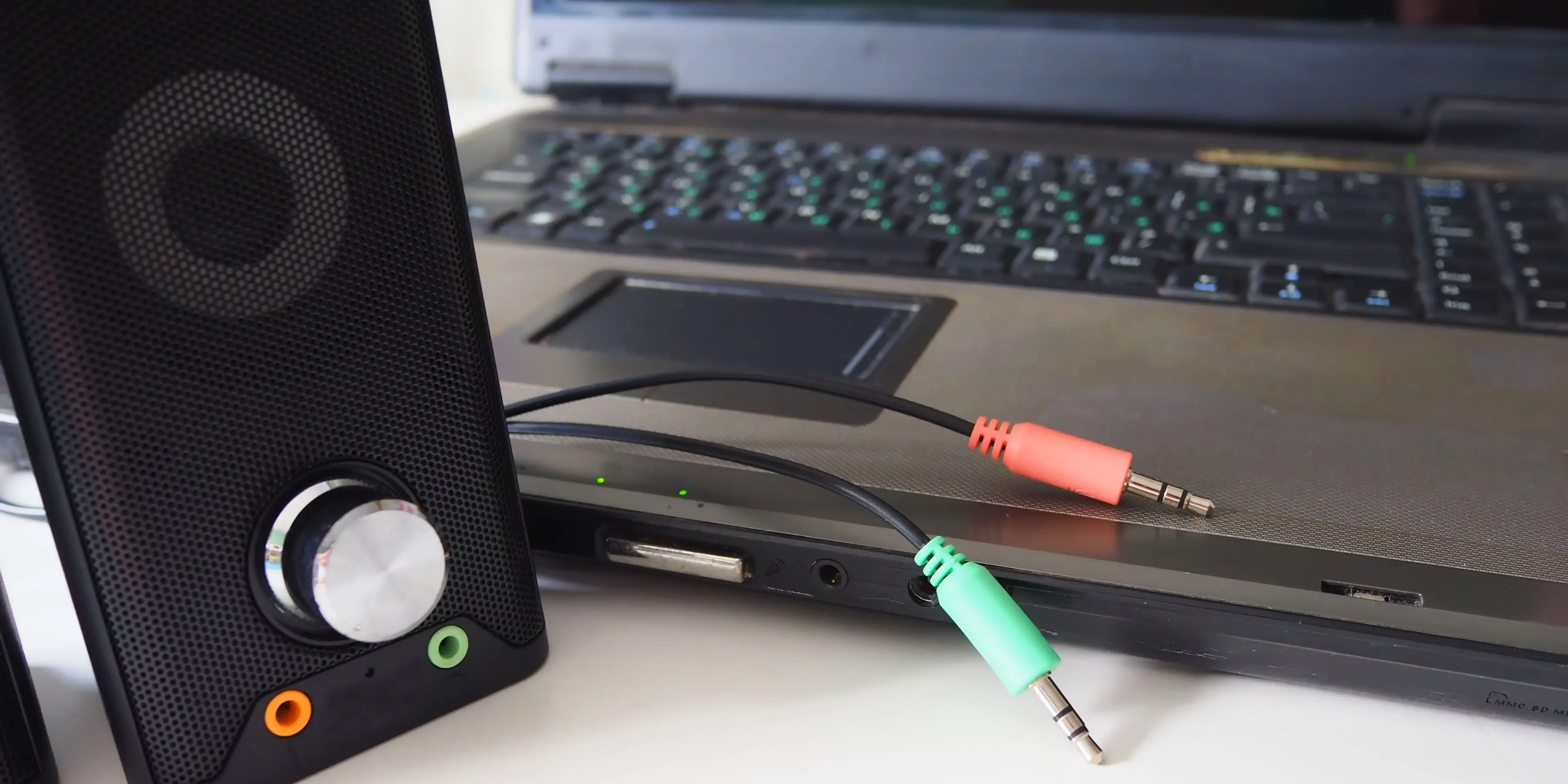 Dây cáp audio 3.5mm và loa đặt cạnh dàn PC, minh họa sự phức tạp của việc quản lý cáp